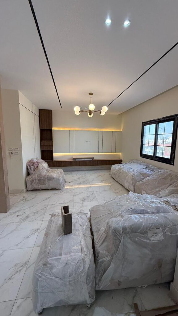 🏡 مشروع تشطيب شقة في الشيخ زايد – أمام بيفرلي هيلز

في المشروع ده اشتغلنا على شقة مساحتها 180 متر في الشيخ زايد – أمام بيفرلي هيلز، وكان المطلوب تشطيب سوبر دي لوكس بالكامل، بتصميم مودرن بسيط وراقي.

مدة التنفيذ كانت شهرين فقط، وركزنا خلالها على إن كل تفصيلة تطلع مظبوطة وتليق بالعميل.

🔧 مراحل التنفيذ والتحديات:

أول ما استلمنا الشقة كانت فيها شوية مشاكل فنية، أهمها:

السباكة القديمة كانت غير صالحة، فتم تغييرها بالكامل من البداية للنهاية.

بعض الحيطان كان فيها ميول، فتم تكسيرها وإعادة المحارة من جديد عشان نرجع التوازن.

كمان عدّلنا أماكن بعض العناصر حسب احتياج العميل لتوزيع أفضل للفراغات.

🧱 الخامات المستخدمة:

السيراميك من كيلو باترا، لونه أبيض رخامي فخم يعطي وسع وأناقة.

التجاليد من خشب MDF بلمسة طبيعية بتكسر اللون الأبيض وتعطي دفء للمكان.

الدهانات من جوتن، بألوان هادية ومريحة للنظر.

✨ النتيجة النهائية:

النتيجة كانت تشطيب على مستوى عالي جدًا — من أول الأرضيات، للأسقف الجبس بورد بخطوط الإضاءة المخفية، لحد تشطيب الحوائط بالتشطيب الخشبي.
تم تسليم الشقة زي ما العميل كان متخيلها وأكثر، وده أهم مبدأ بنعتمد عليه في كل شغلنا:

“نسلّم الشقة كما يستحق العميل.”